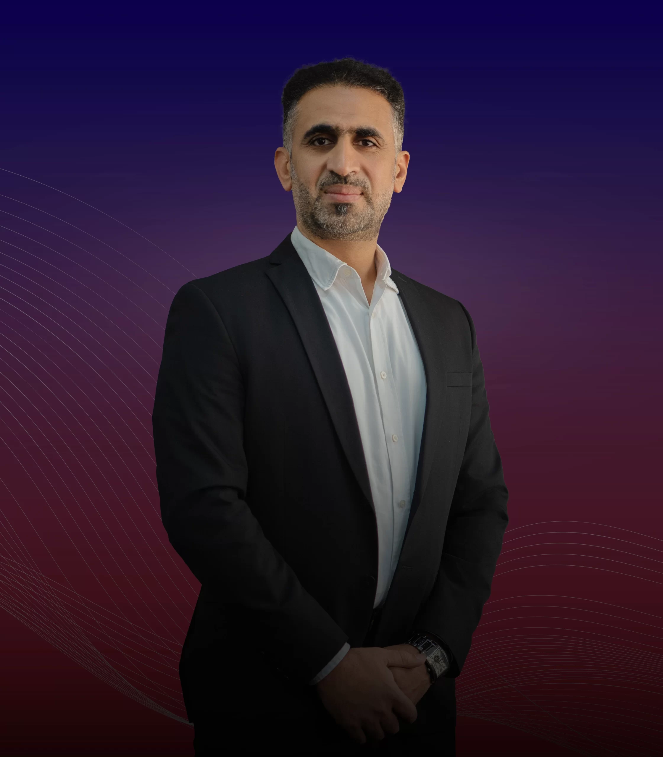 A man in a suit standing confidently against a striking red and blue background, personifying elegance and professionalism as Hussain Derazi.